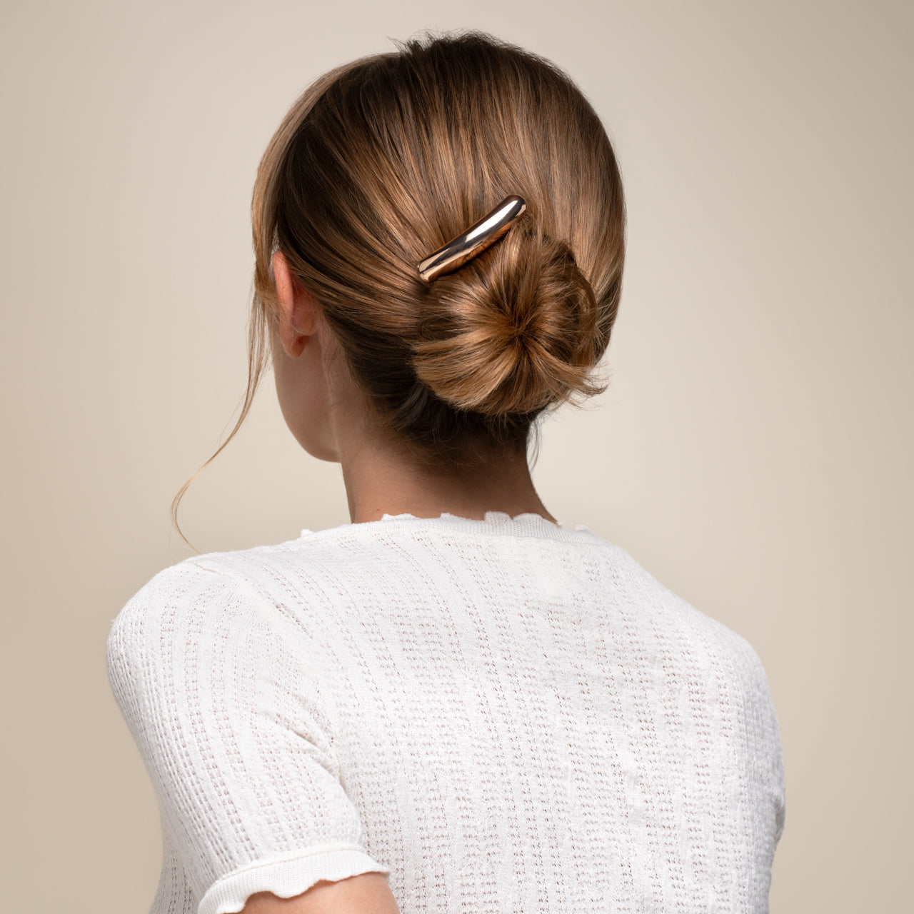 Person with a hair clip in their bun against a neutral background