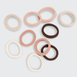 Set of cream, beige, blush, and brown hair ties on a light gray background