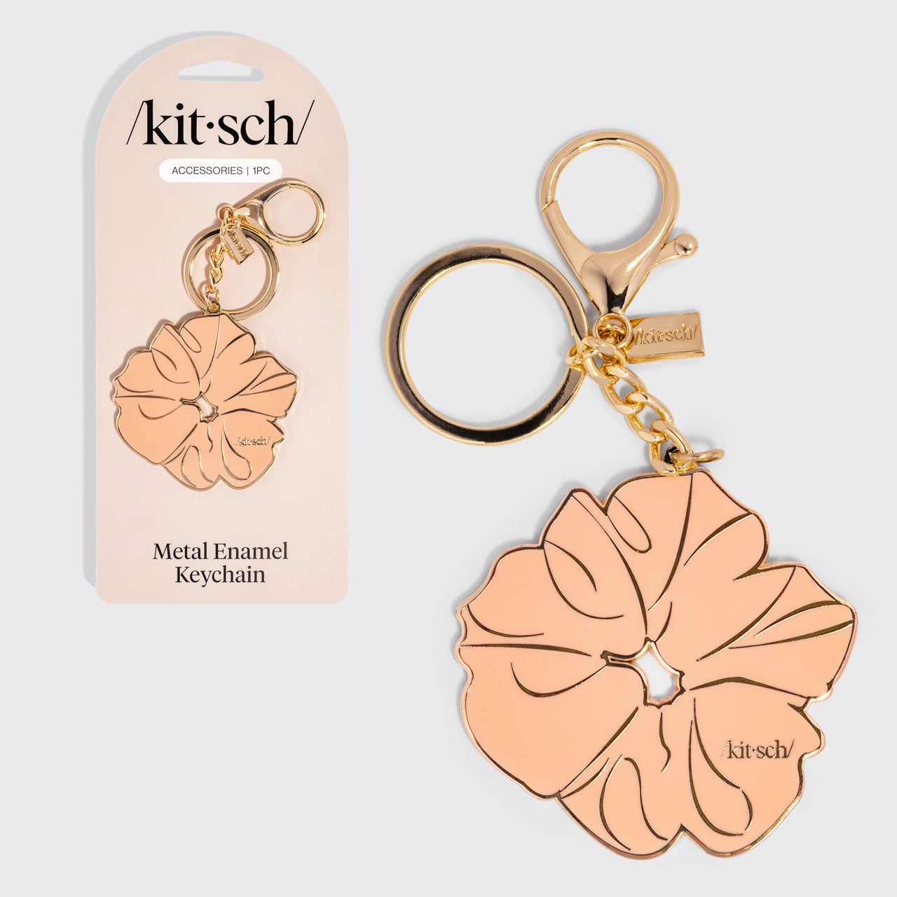 Metal enamel keychain depicting the kitsch Terracotta Scrunchie with gold outline, design, and hardware with packaging on a light gray background