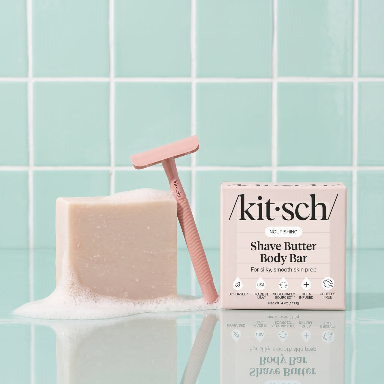 Perfect Glide Safety Razor with Nourishing Shave Butter Body Bar and packaging displayed beside foamy lather on a bathroom countertop.